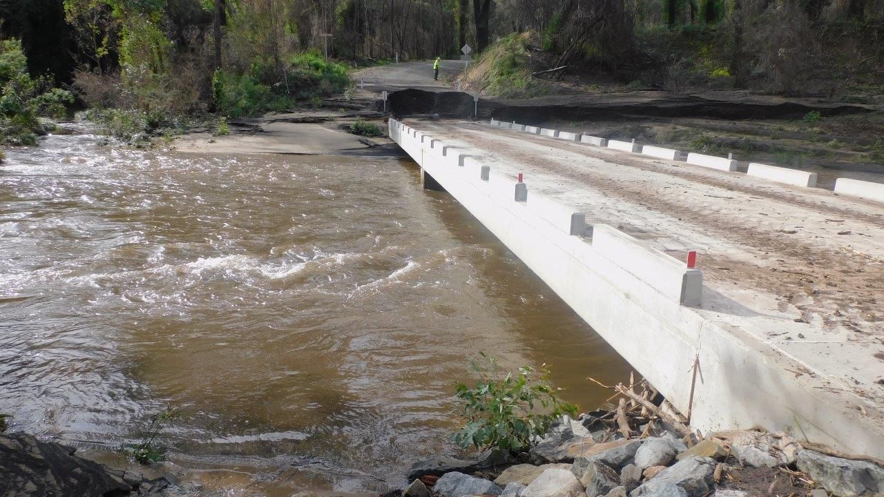 Image shows the concrete bridge after the July 2020 flood on the right of shot, which is covered with a small amount of sediment on the deck but is otherwise unaffected by the flood.