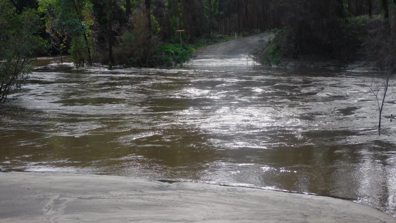 The Rocky River Road Bridge is submerged by the Brodribb River but remained intact despite a high volume of debris washed into the river. Image shows the approach road to the bridge and flood water that has submerged the new bridge.