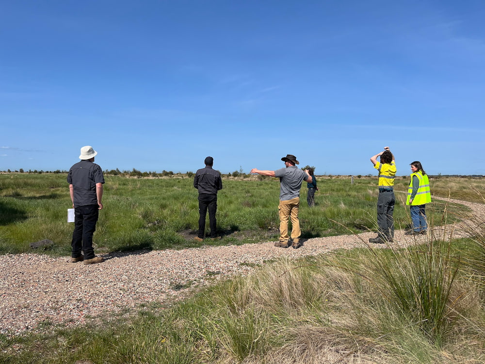 Photo of people standing in loose group on a gravel path with green grass either side