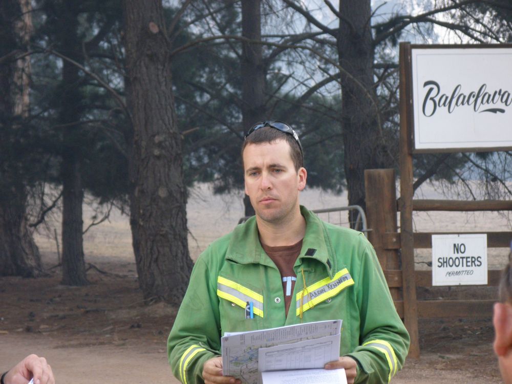 Aaron outside in FFMVic uniform holding map and papers