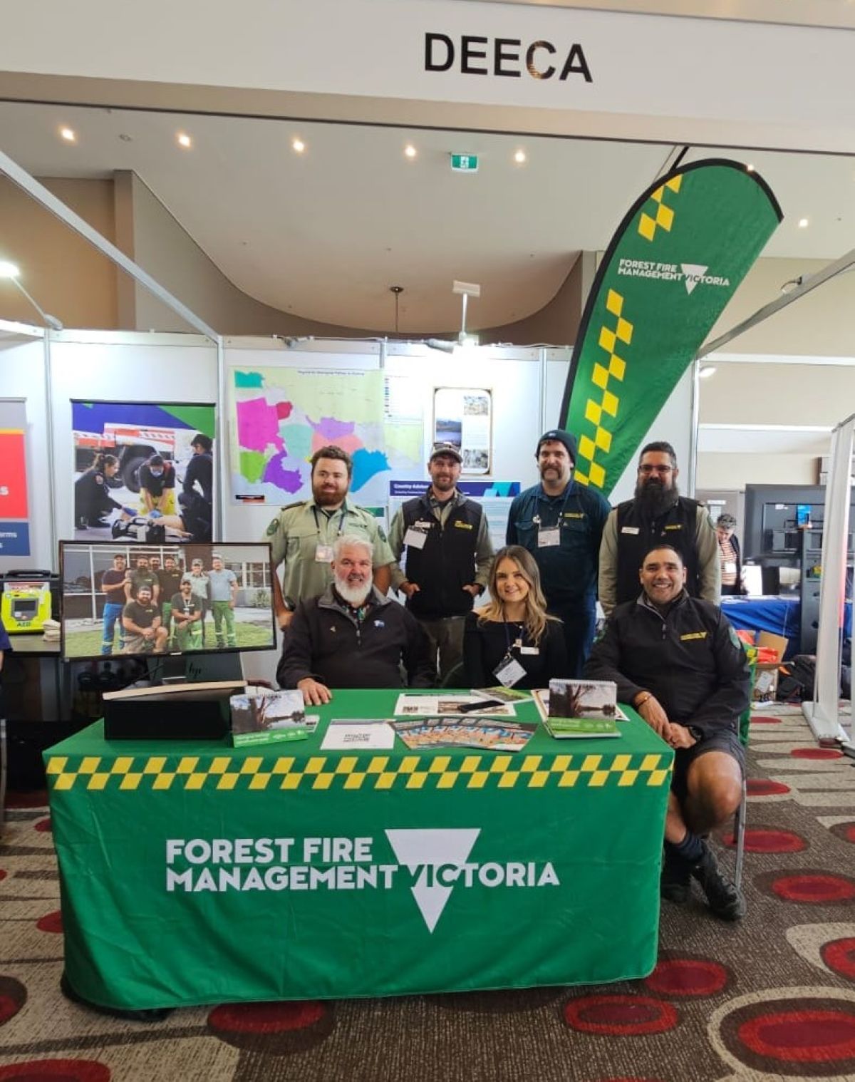 Manny, Caleb, Tom, Trent, Levi, Tahlia and Damien posing for a group photo at the DEECA stand