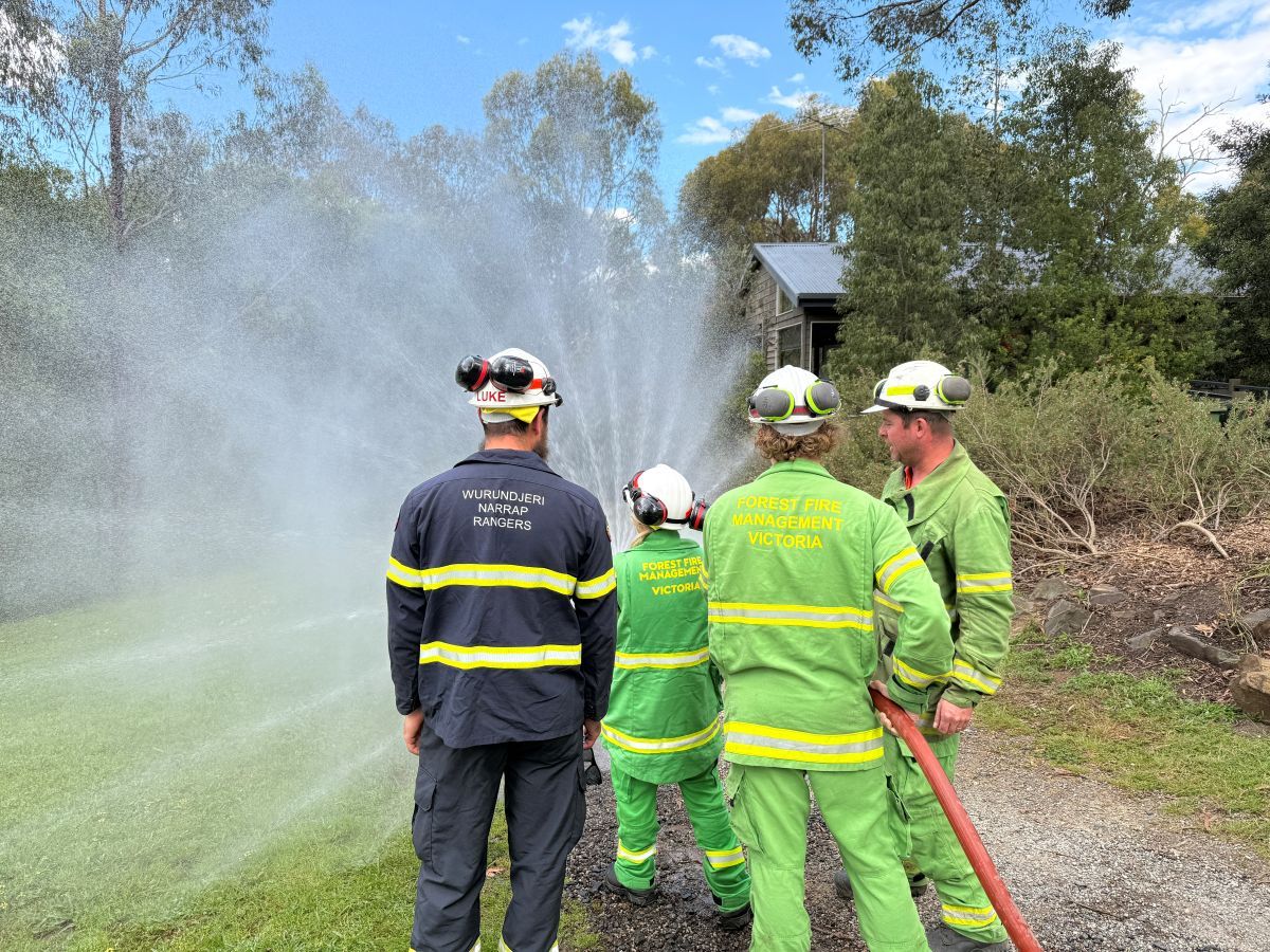A group of three trainees practising with a hose